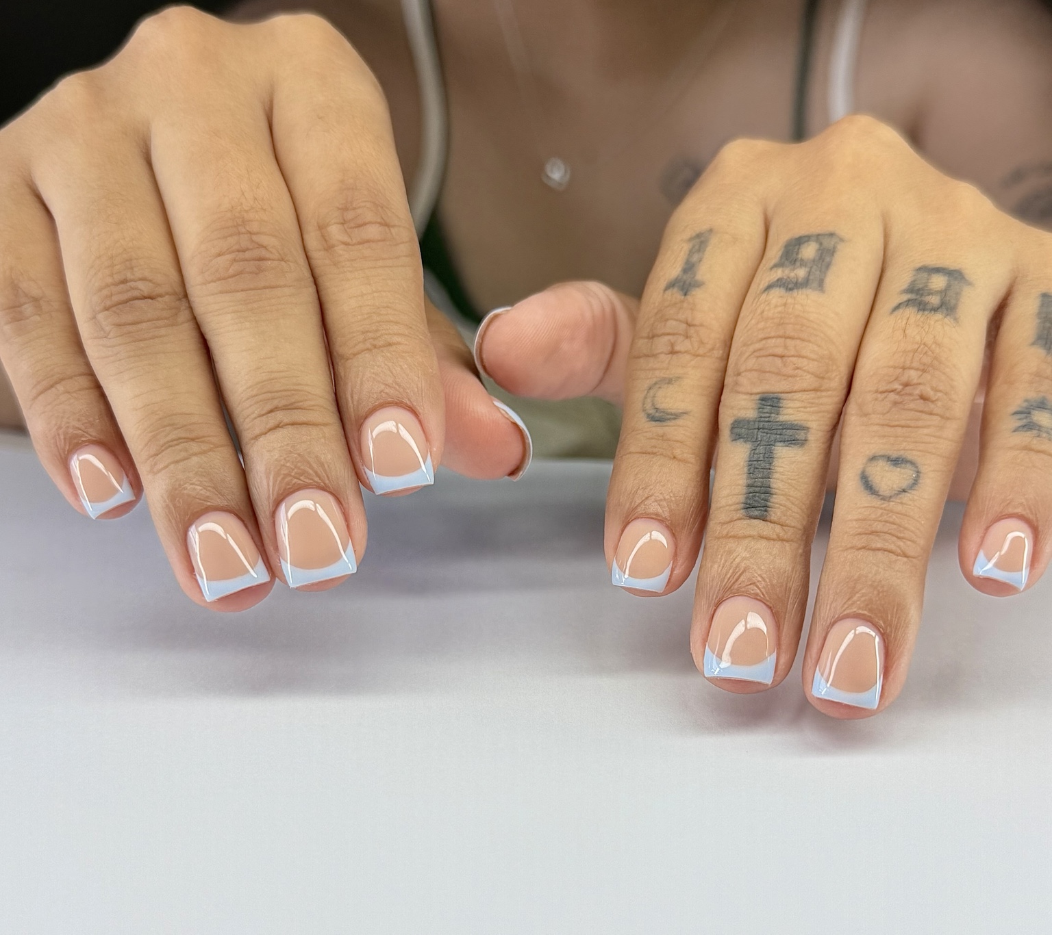Short square nails on both hands with glossy nude bases and pale blue French tips